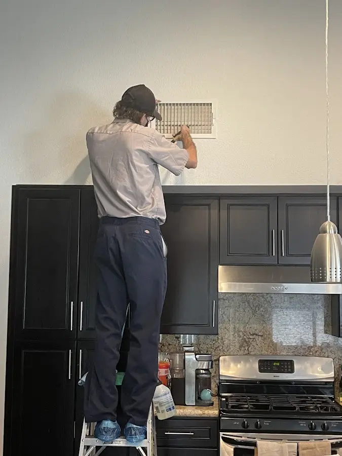 Technician inspecting an air vent during HVAC service in Smithfield